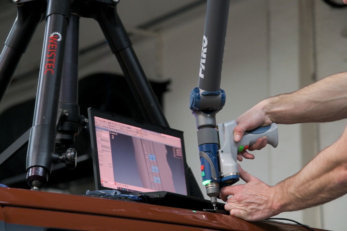 FARO portable CMM arm scanning a part with live results on a laptop